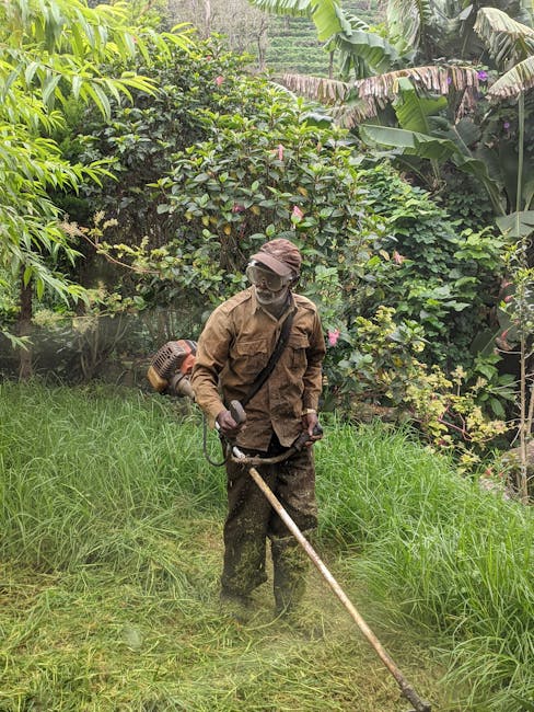 A landscape worker cutting tall grass with a string trimmer